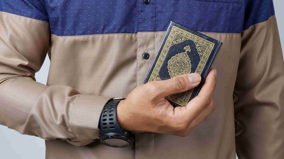 Man holding small Quran in one hand
